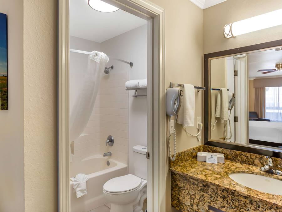 A bathroom with a bathtub, toilet, and a sink with a marble countertop.