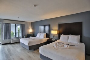 A hotel room with two beds, a large window with curtains, a ceiling light, and a bedside table with a lamp. - Best Western Surf City (Huntington Beach)