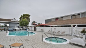 A pool area with a hot tub, lounge chairs, and a covered seating area. - Best Western Surf City (Huntington Beach)