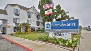 A Best Western hotel sign with the address 19360, surrounded by a landscaped garden with flowers and a flagpole with two flags. - Best Western Surf City (Huntington Beach)