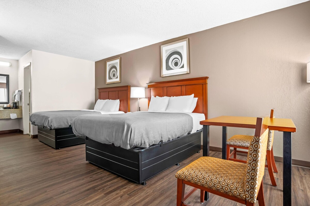 A hotel room with two beds, a desk, and a chair.
