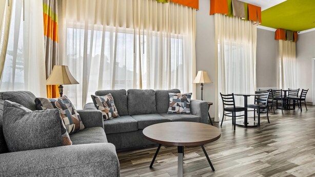A modern living room with a sofa, round coffee table, and dining area with chairs. - Quality Inn Louisville MS (Louisville)