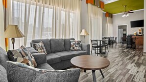 A living room with a sofa, armchair, and round table, a dining area with chairs, a kitchen area, and a ceiling fan. - Quality Inn Louisville MS (Louisville)
