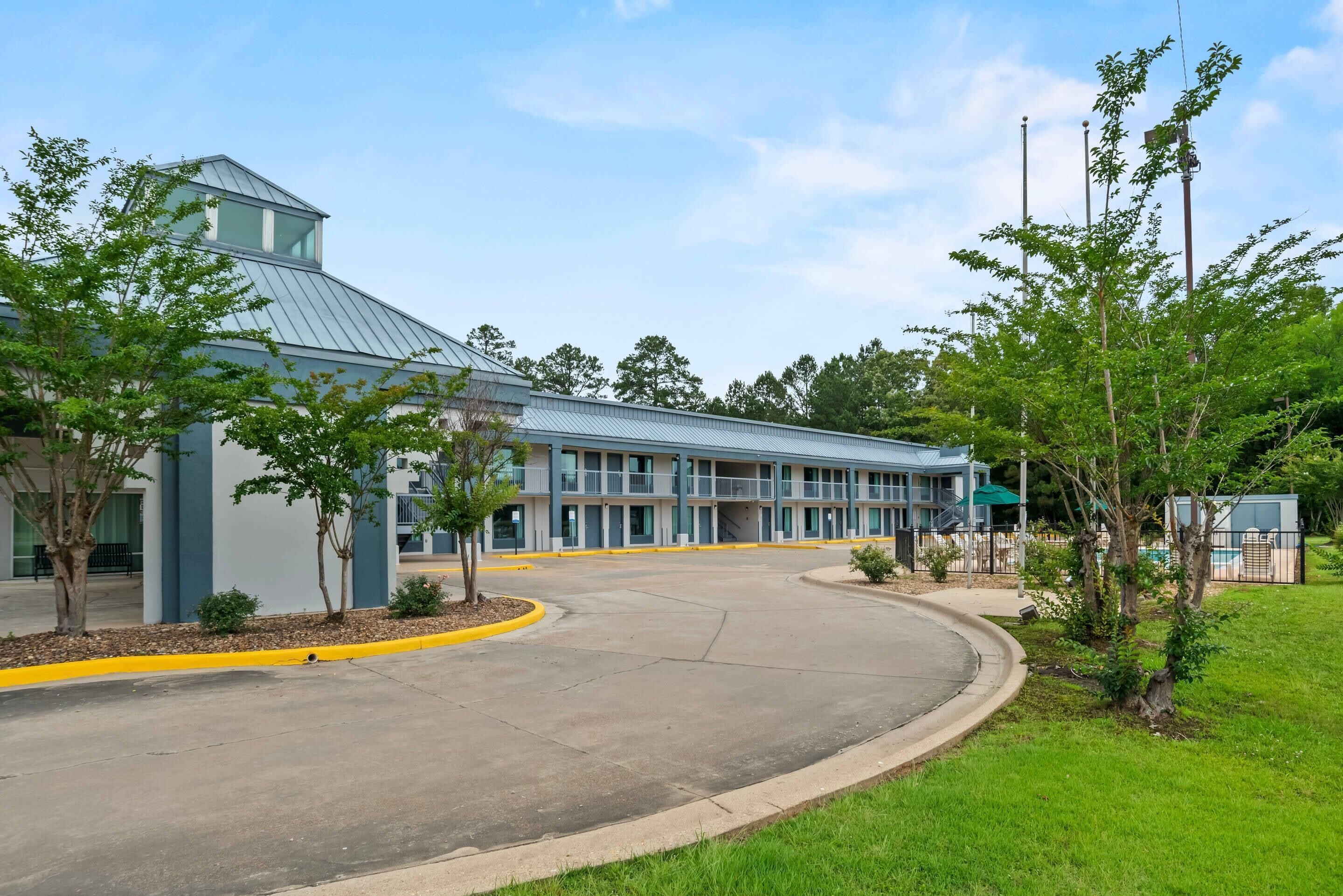 A modern building with a curved driveway, a covered parking area, and a landscaped entrance.