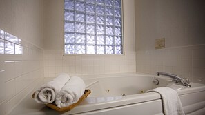 A bathroom with a bathtub, a window with frosted glass, and a towel rack.