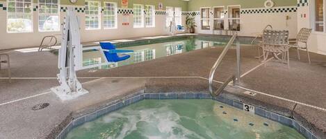 An indoor swimming pool with a water slide, lounge chairs, and a lifeguard station.