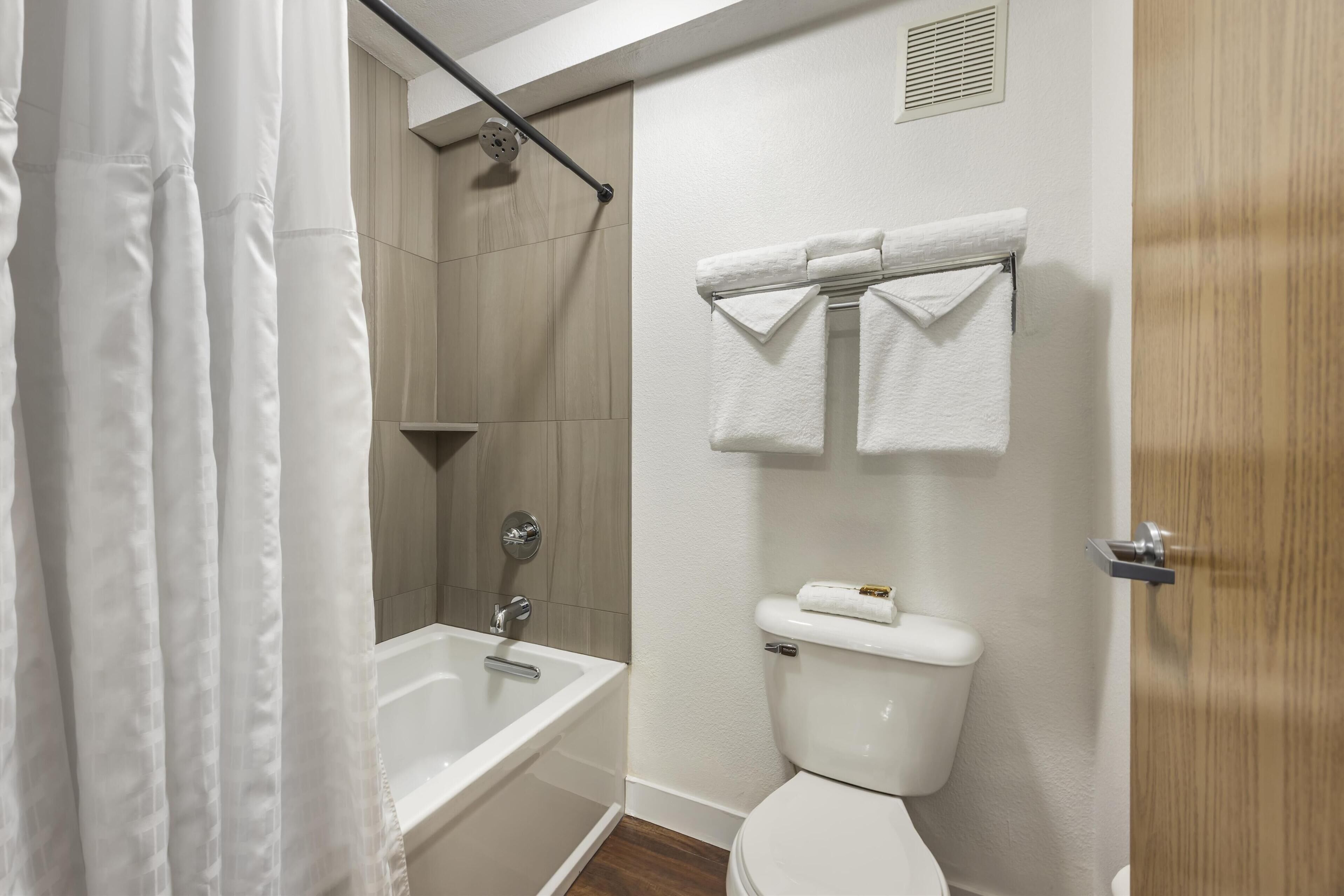 A modern bathroom with a bathtub, toilet, and shower.