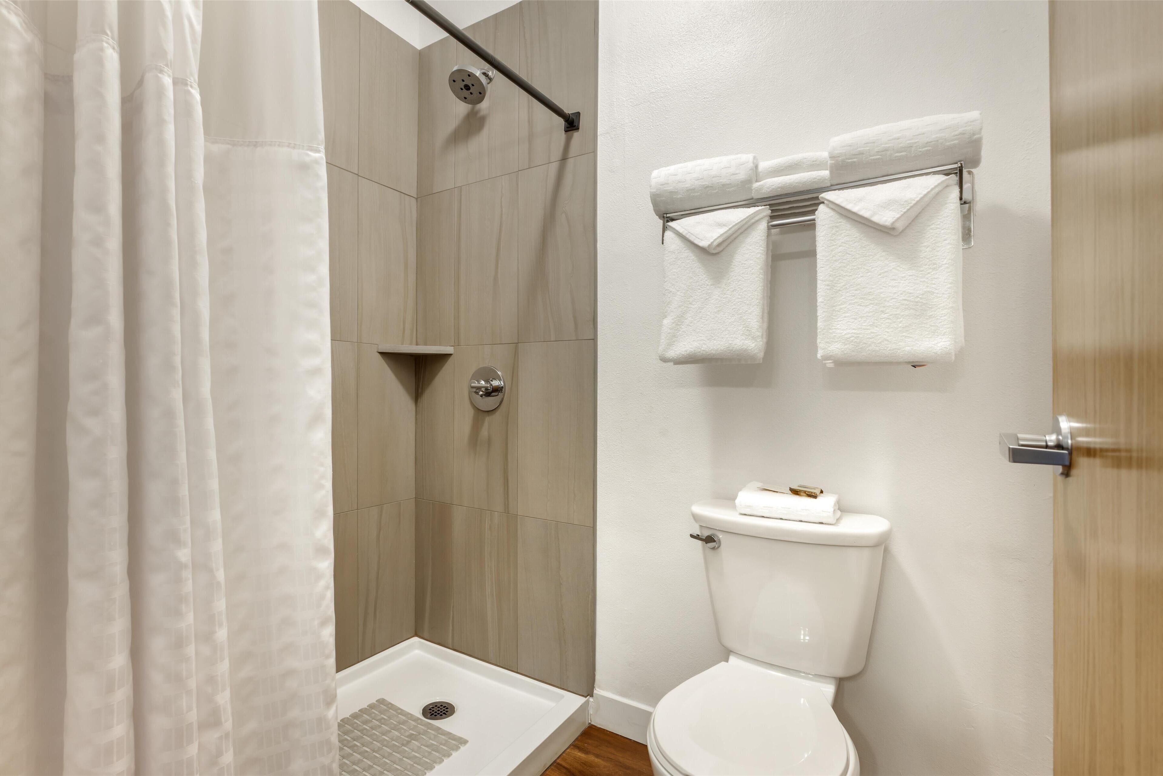 A modern bathroom with a shower, toilet, and towel rack.