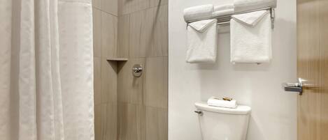 A modern bathroom with a shower, toilet, and towel rack.