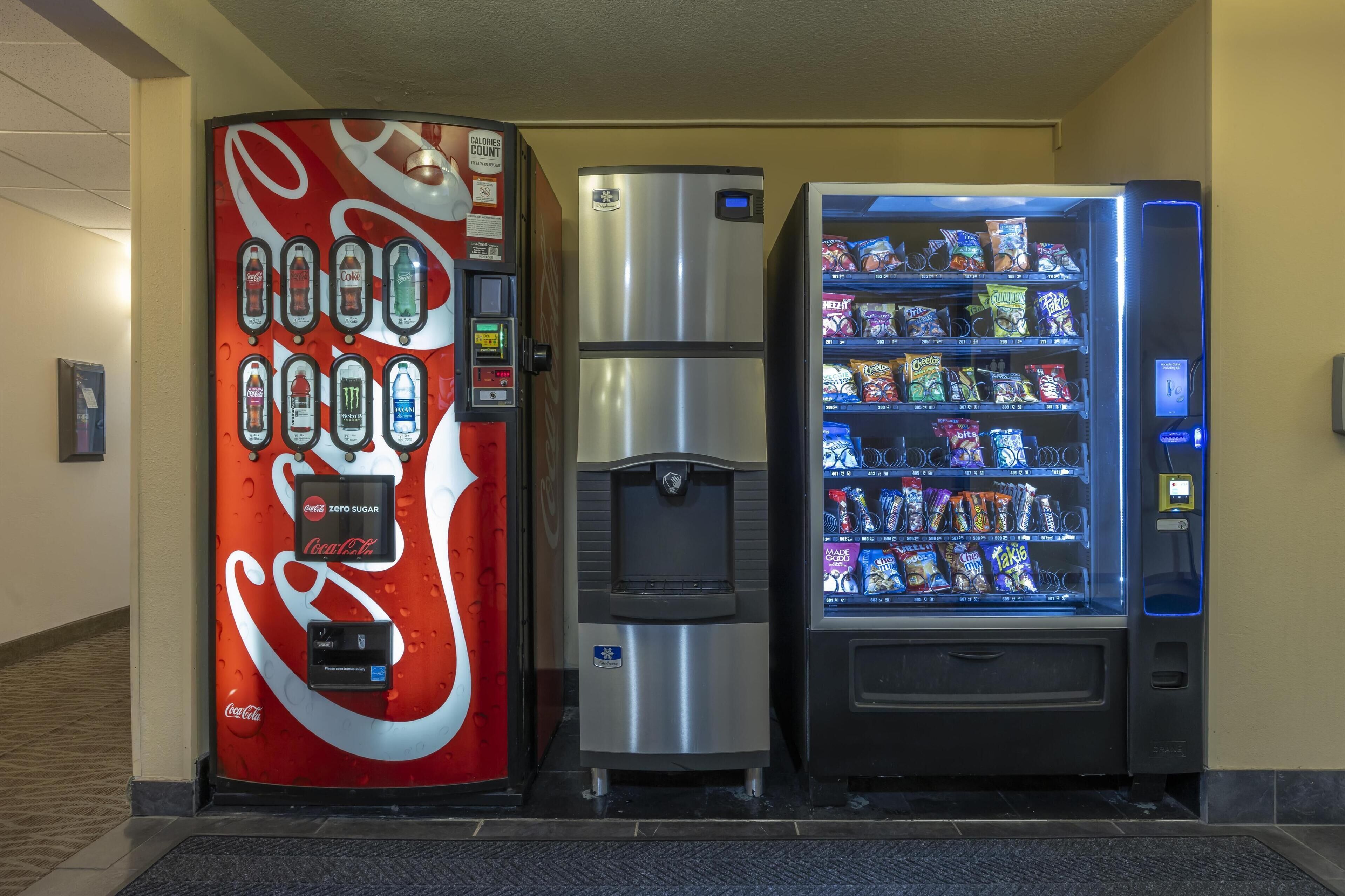 Een automaat met snacks en een Coca-Cola automaat met een waterdispenser.