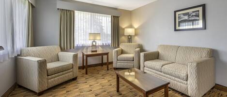 Una habitación de hotel con dos sofás, una mesa de centro, una mesita auxiliar y una lámpara.