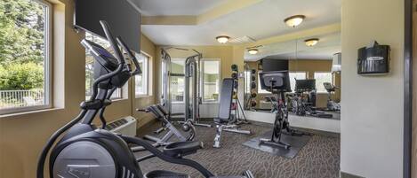 A gym with cardio machines, weight equipment, and mirrors.
