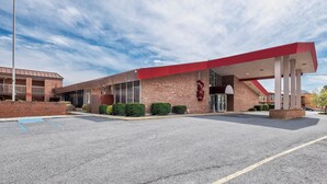 Un bâtiment doté d’un toit rouge et d’une façade en briques, avec une grande entrée et un parking.