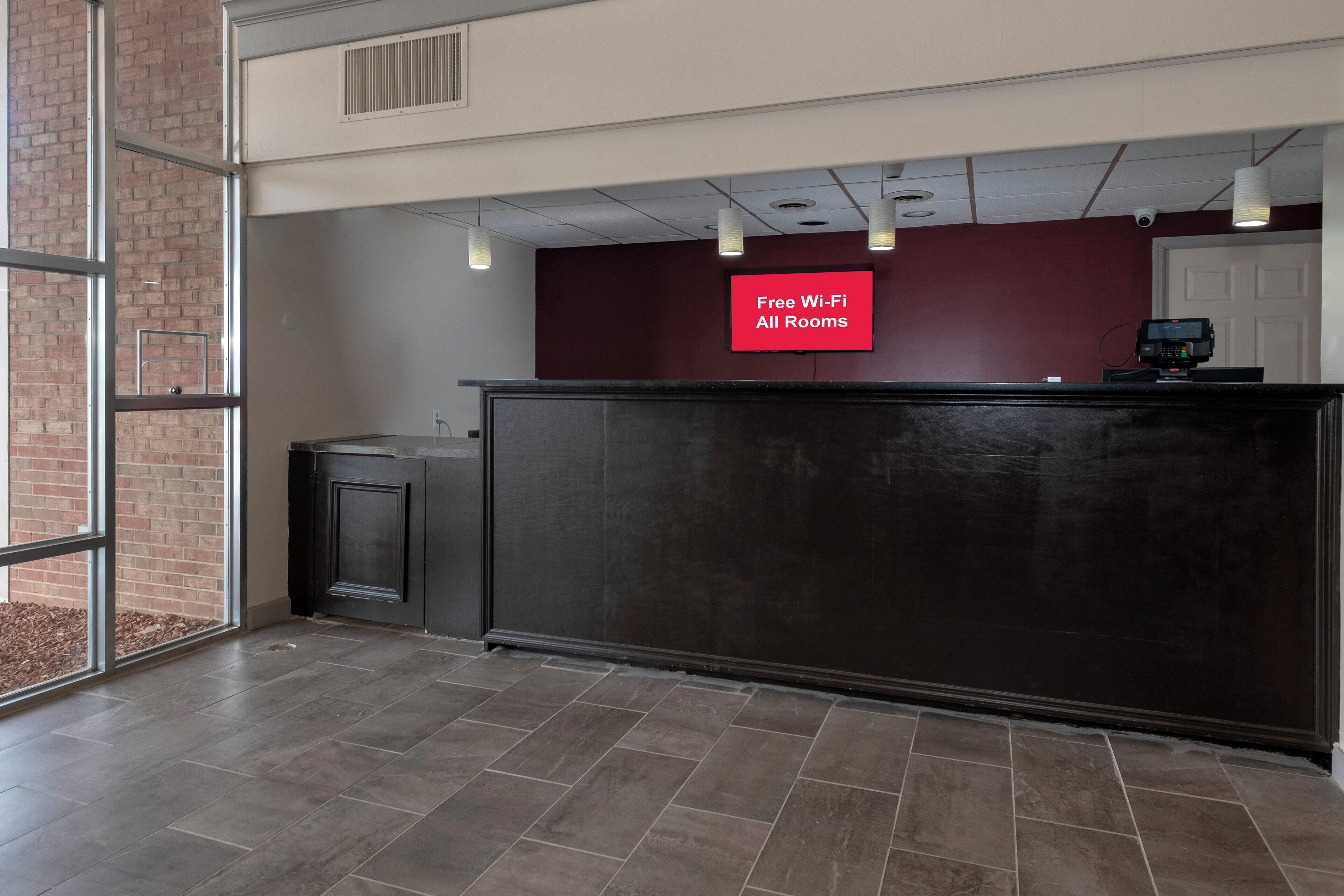 A reception area with a 'Free Wi-Fi All Rooms' sign, a reception desk, a trash bin, and a door.
