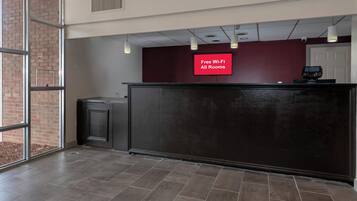 A reception area with a 'Free Wi-Fi All Rooms' sign, a reception desk, a trash bin, and a door.