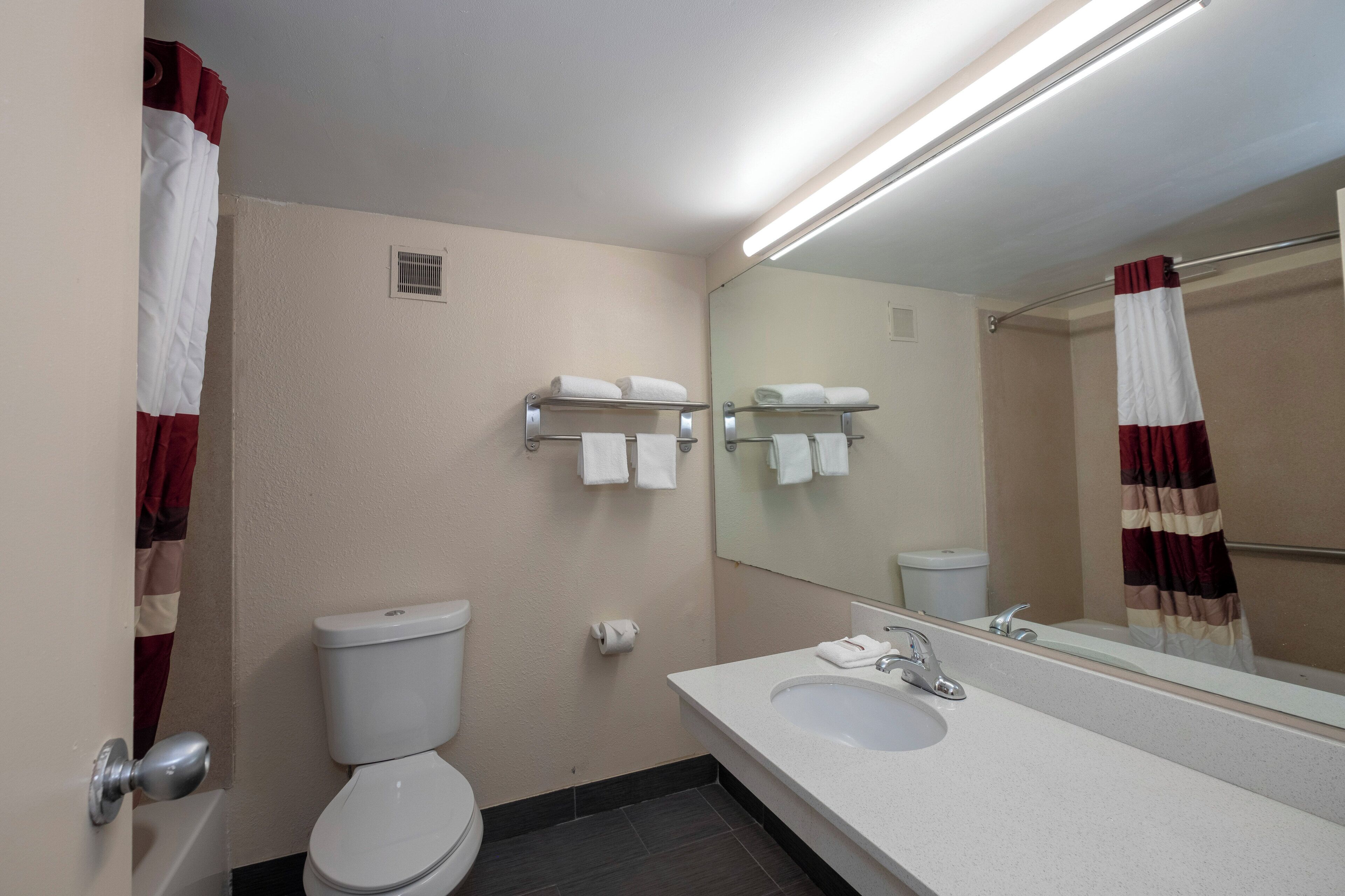 A bathroom with a toilet, sink, and towel racks.