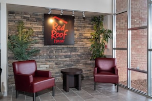 A Red Roof Inn sign on a stone wall, two leather chairs, a small table, and potted plants. - Red Roof Inn Marion, VA (Marion)