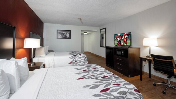 Une chambre d’hôtel avec deux lits, un bureau, une télévision et une chaise.