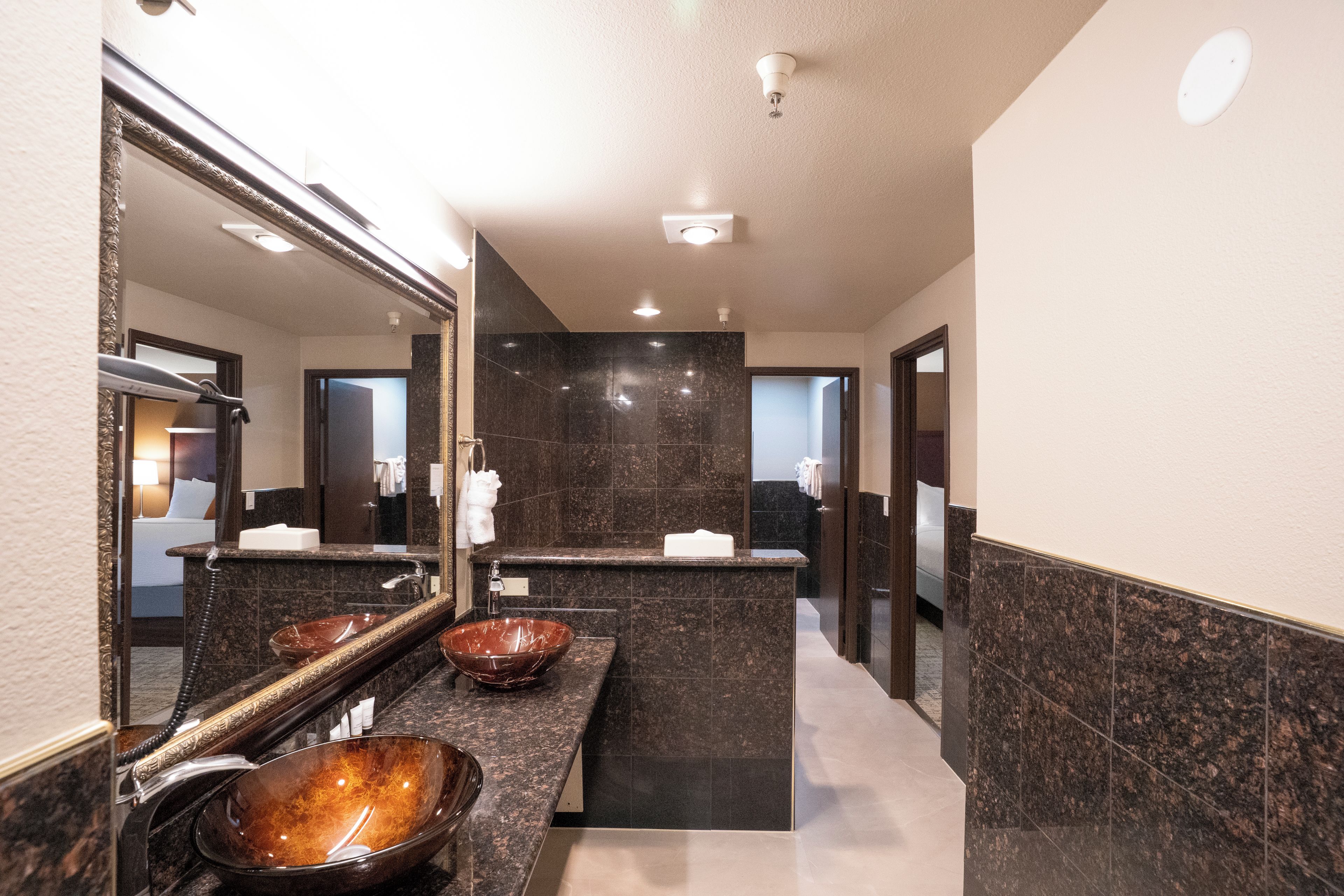 A modern bathroom with a large mirror, a vessel sink, and a marble-tiled wall.