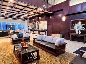 A spacious lobby with leather sofas, a marble coffee table, and a patterned carpet. - Ramada by Wyndham Tukwila Southcenter (Tukwila)