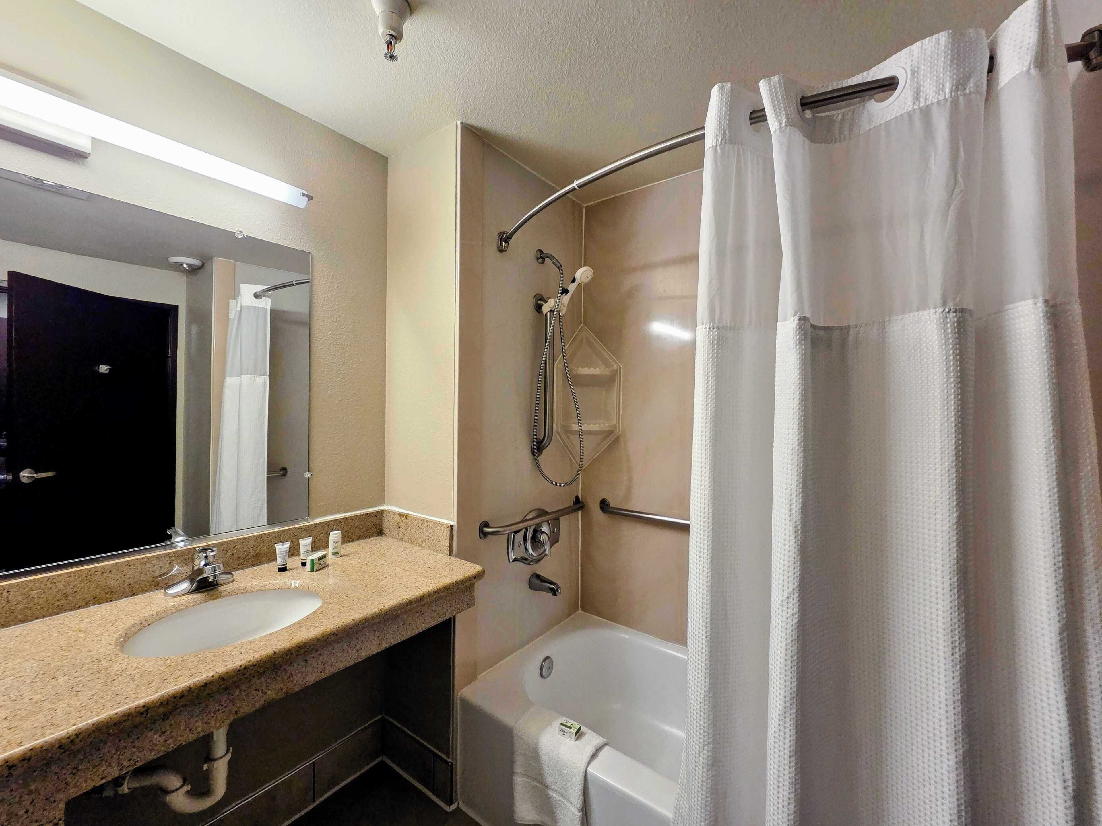 A bathroom with a sink, mirror, shower, and bathtub.
