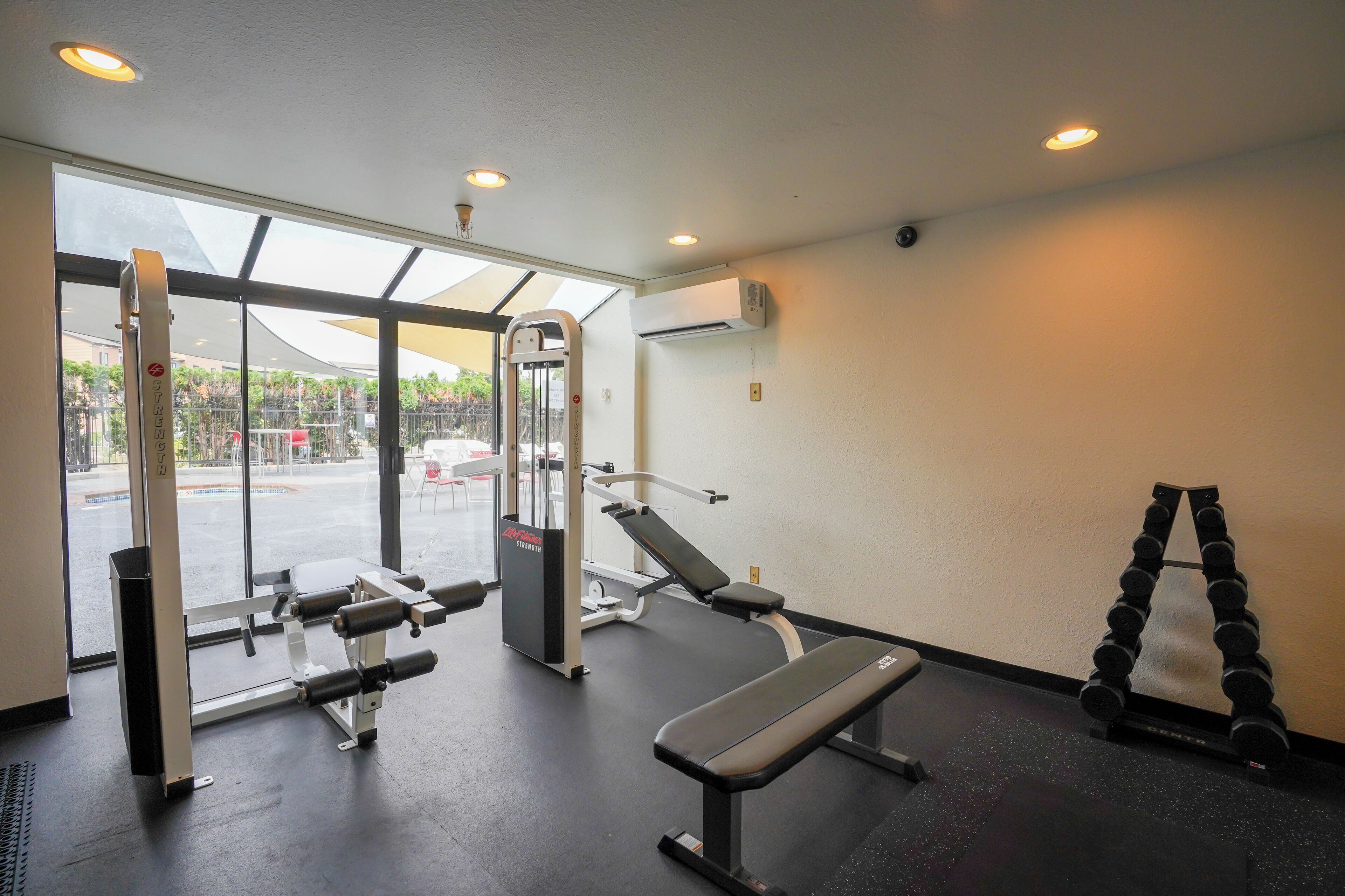 A gym with weight machines, a bench, and a dumbbell rack.