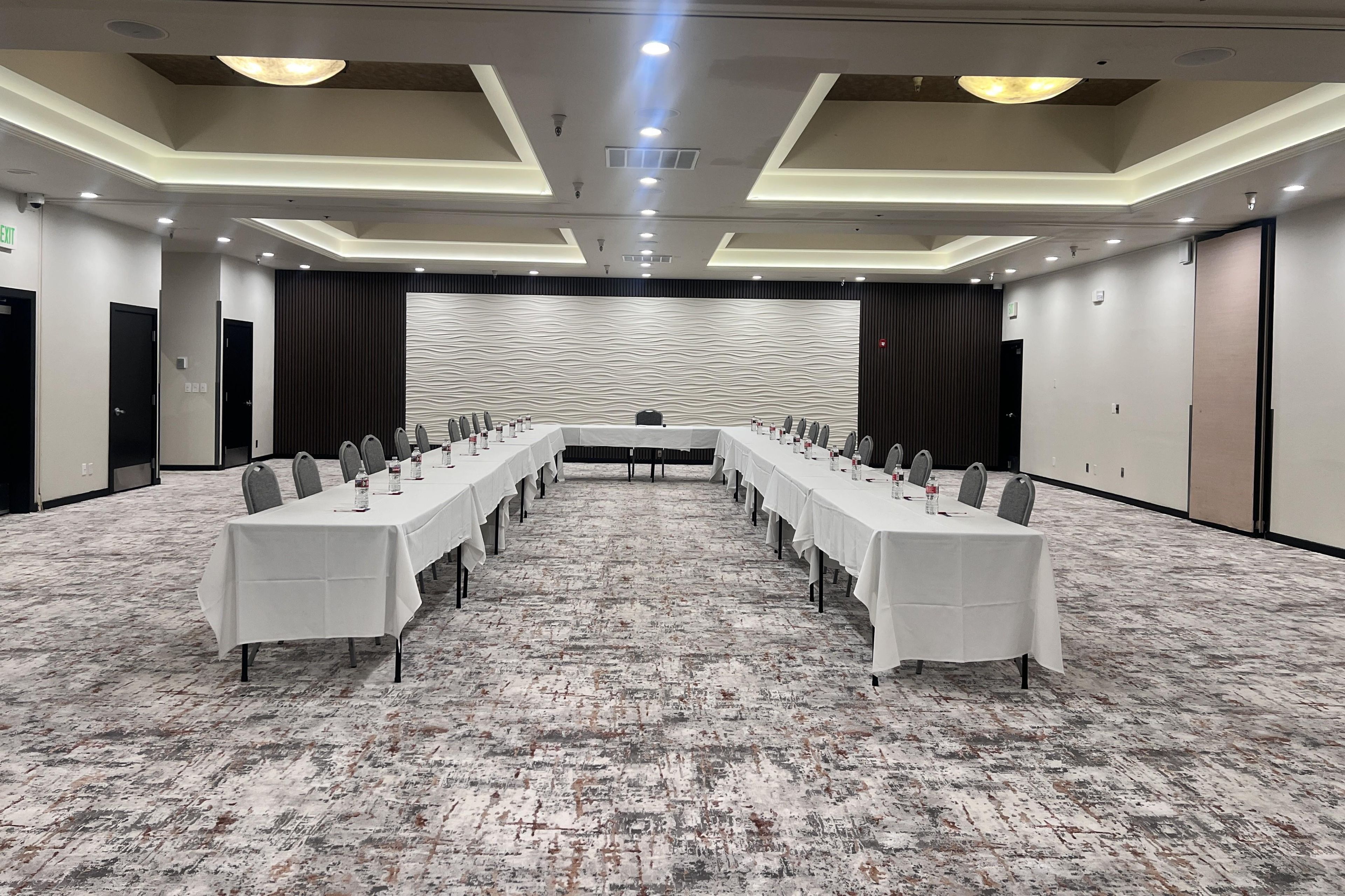 A conference room with a long table, chairs, and a patterned wall.