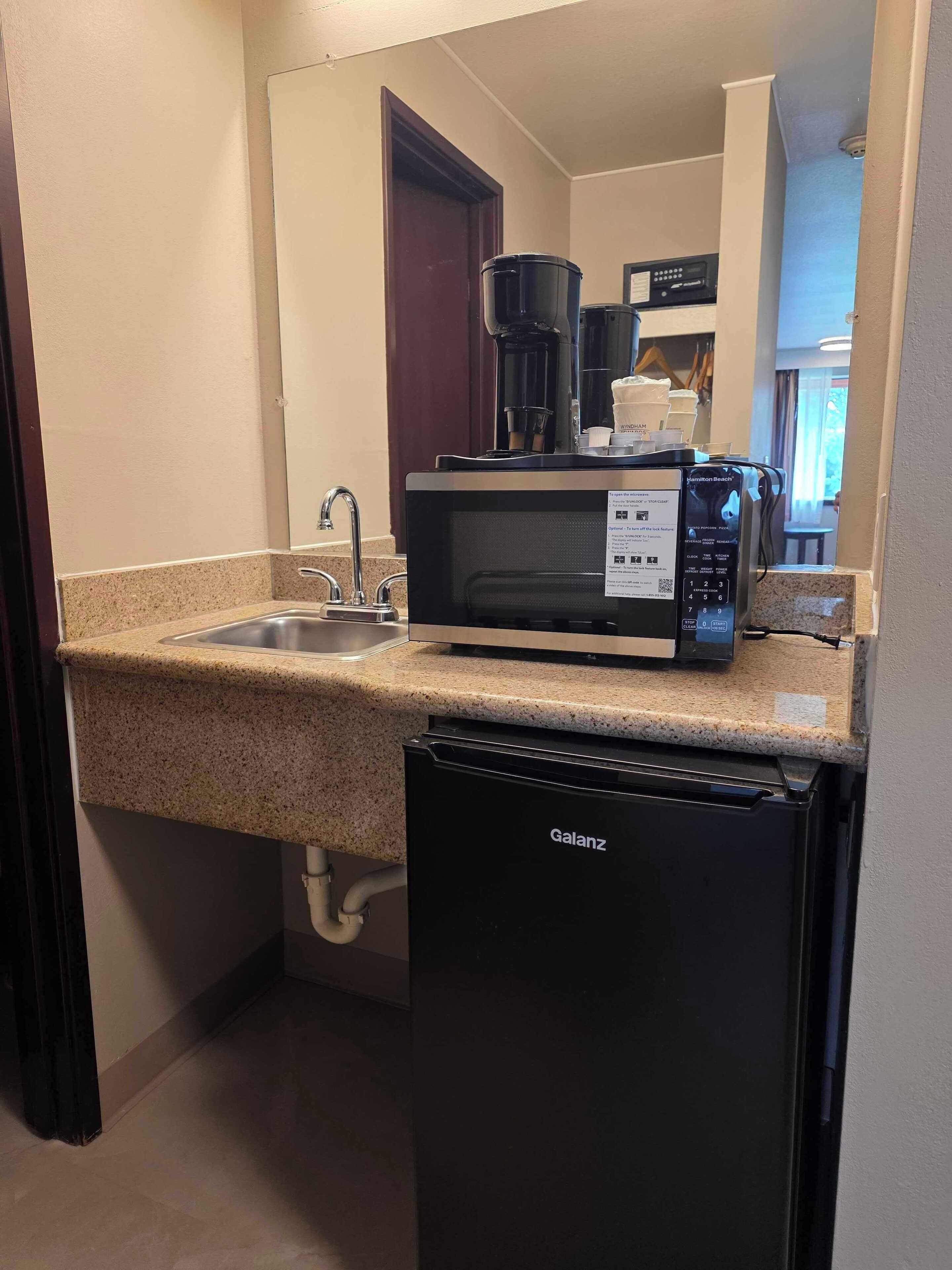 A compact kitchenette with a microwave, coffee maker, and dishwasher.