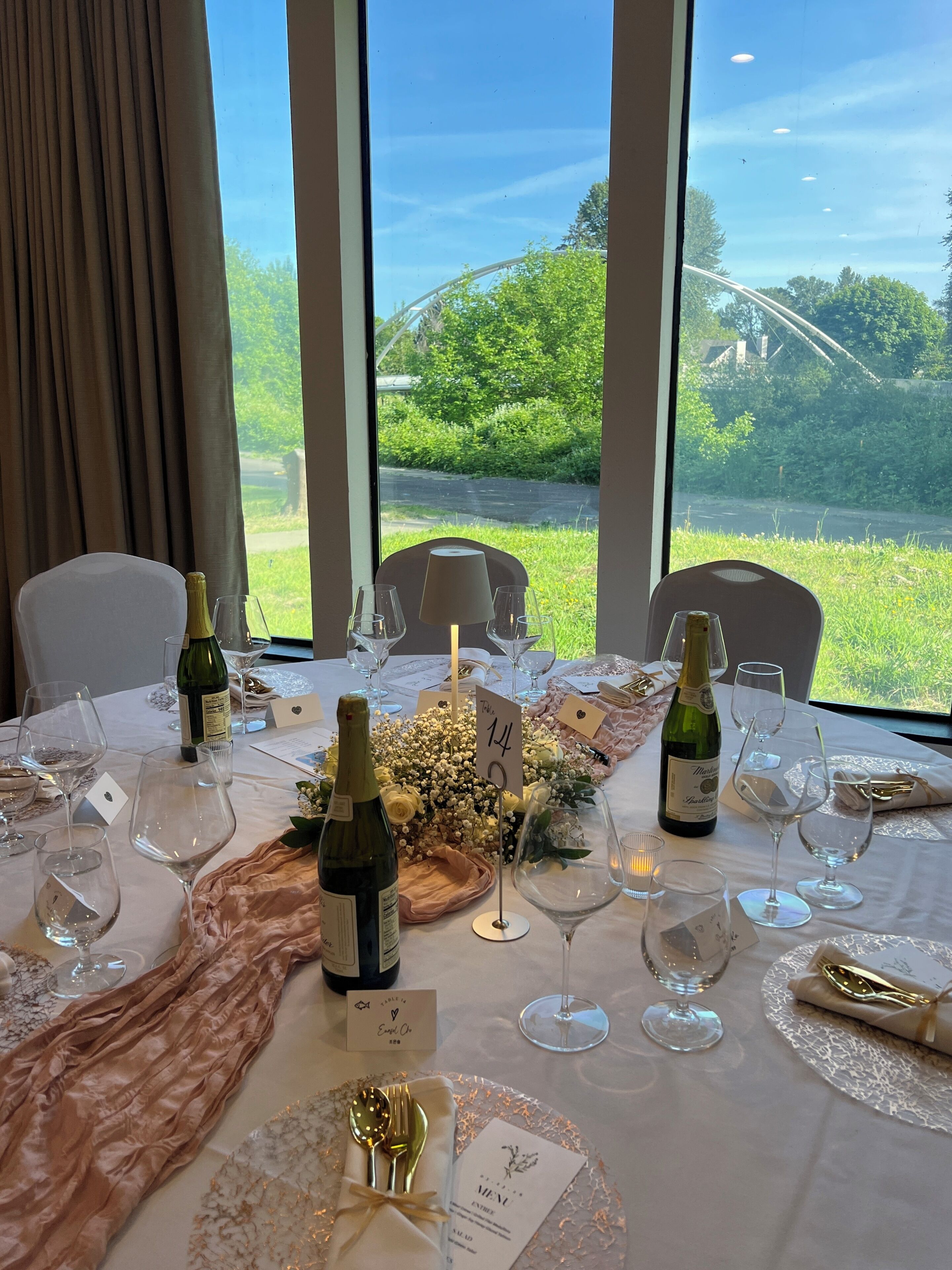 Una mesa lista para una comida con copas de vino, botellas y un menú.