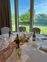 Una mesa lista para una comida con copas de vino, botellas y un menú.