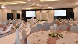 Un salón de banquetes con mesas redondas, sillas cubiertas de blanco y centros de mesa florales.