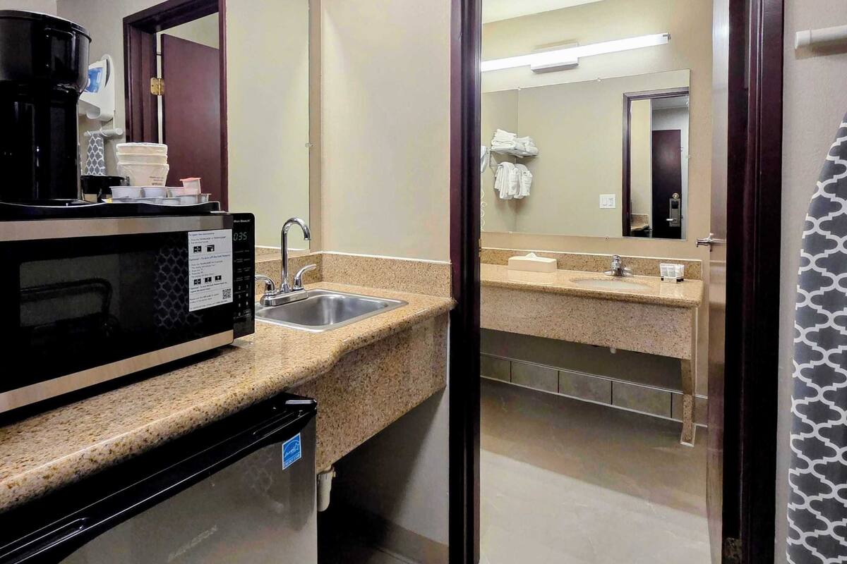 Een hotelbadkamer met een wastafel, spiegel en een magnetron.