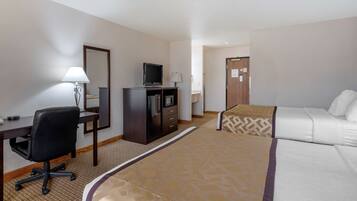 Habitació d'hotel amb llit, escriptori, cadira, televisió, armari i làmpada.