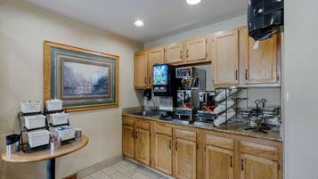 A kitchen with wooden cabinets, a coffee machine, and a small table with containers.