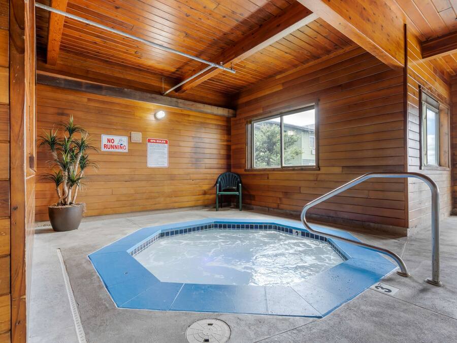 Interior de una cabaña de madera con jacuzzi, paredes de madera, una ventana y un cartel que dice 'No correr'.
