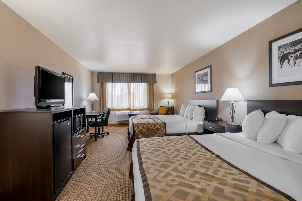 A hotel room with a bed, a desk with a chair, a television, and a window with curtains.