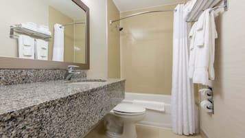 A bathroom with a granite countertop, a toilet, a shower with a glass door, and a towel rack with folded towels.