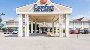 Un Comfort Inn & Suites con una entrada destacada, un estacionamiento y un cielo azul claro.