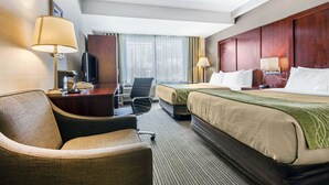 Una habitación de hotel con una cama, dos mesitas de noche, un escritorio con lámpara, una silla, un televisor y una ventana con cortinas.