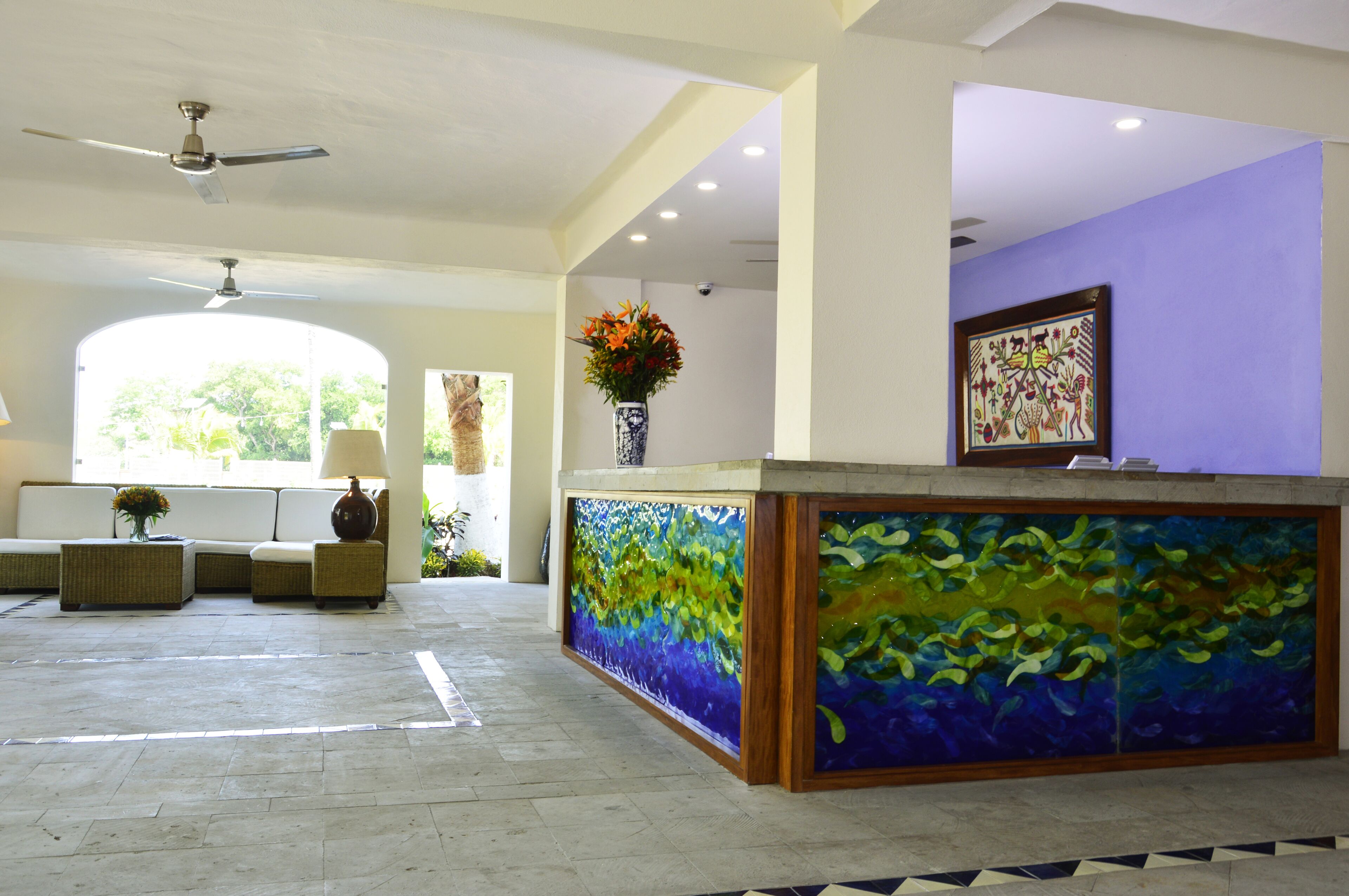 Een receptie met een grote aquariumwand, een plafondventilator en een zithoek met een bank en stoelen.