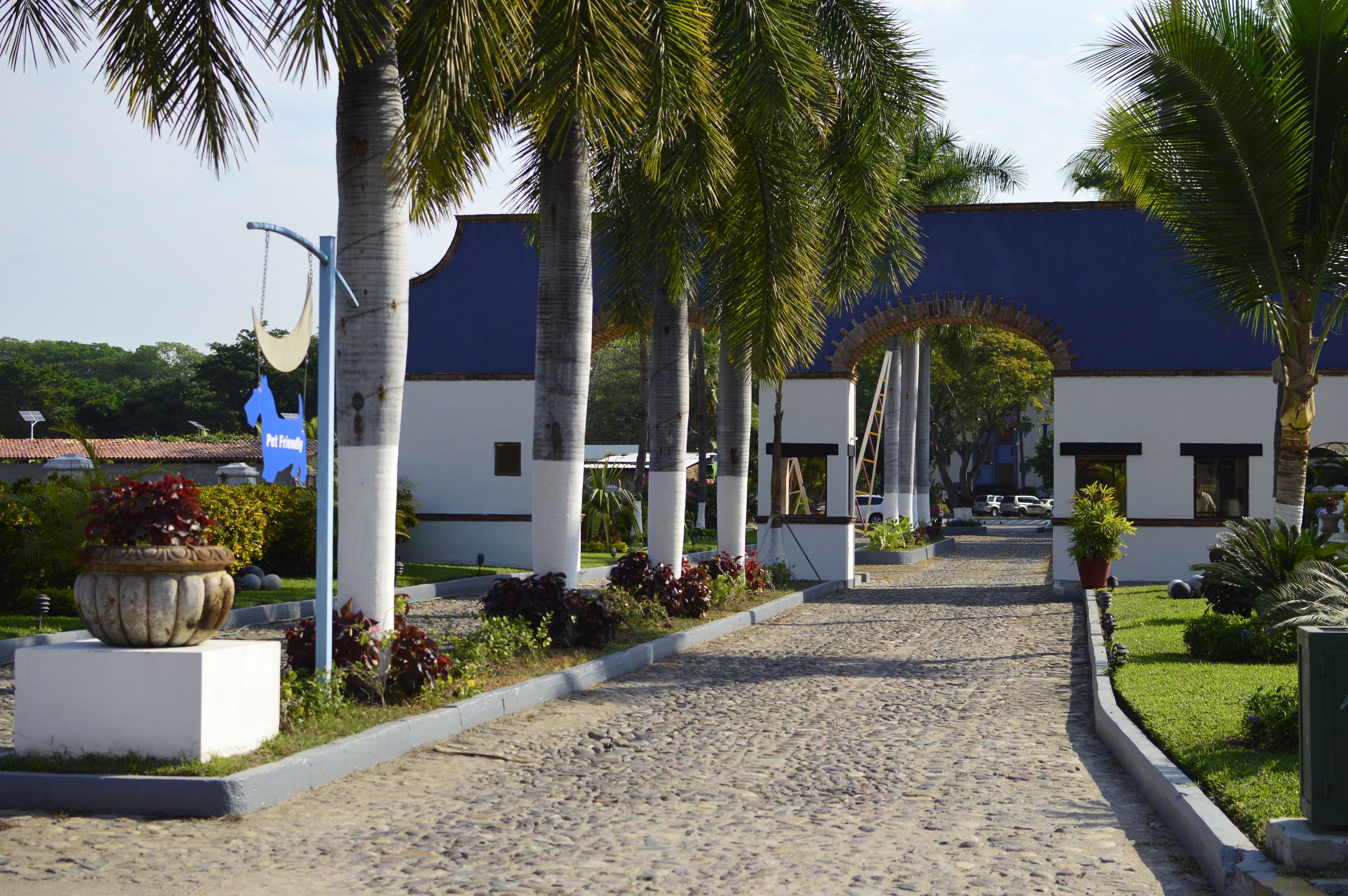 A cobblestone pathway leading to a building with white columns and a blue roof.