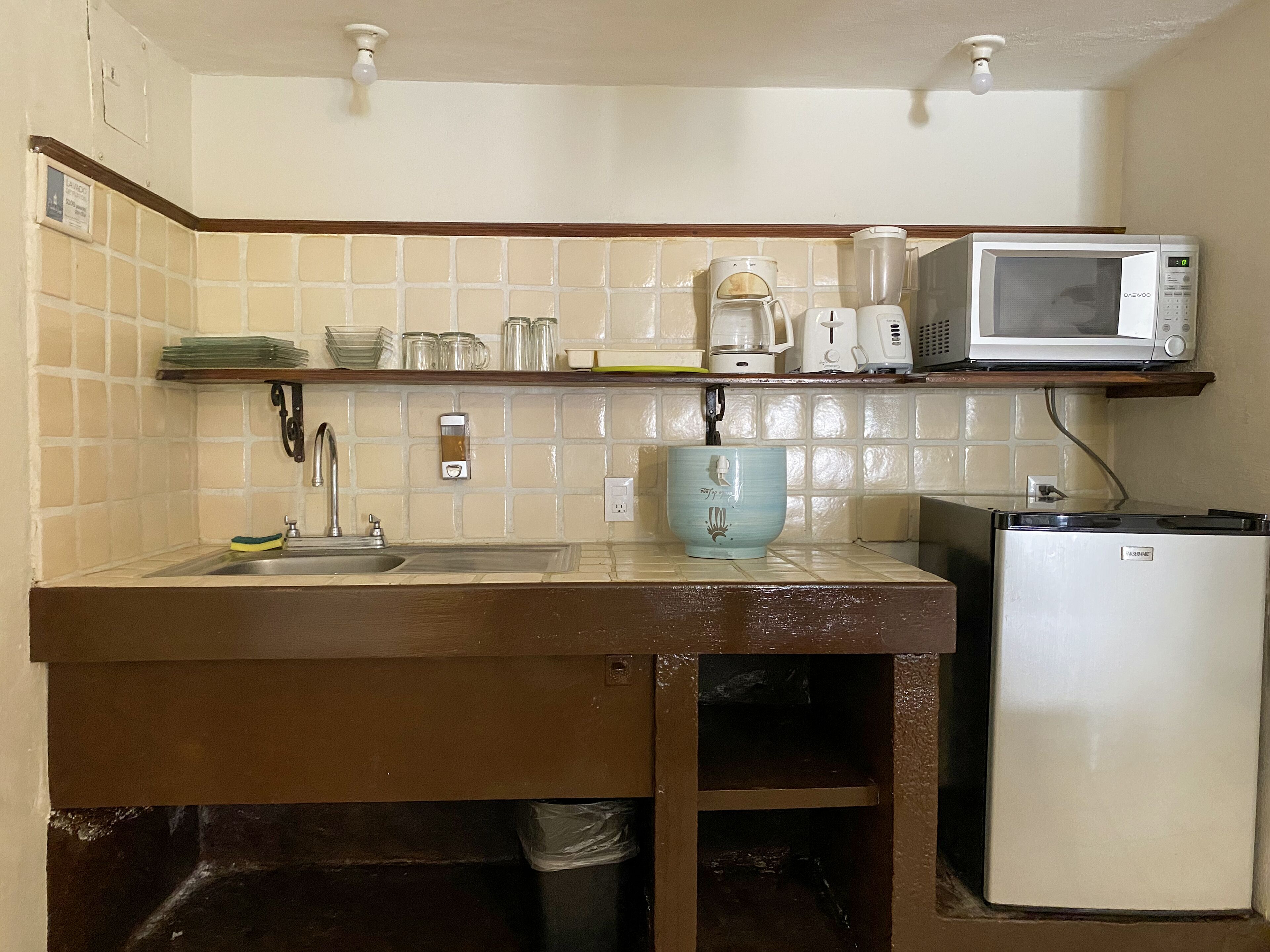 A kitchen with a sink, a coffee maker, a microwave, and a refrigerator.