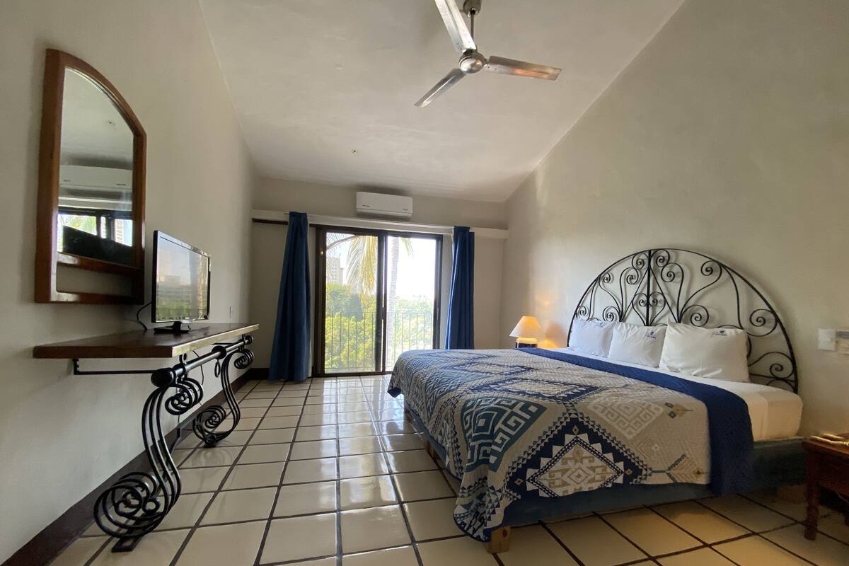 Ein Hotelzimmer mit Bett, Fernseher, Deckenventilator und Blick ins Freie.