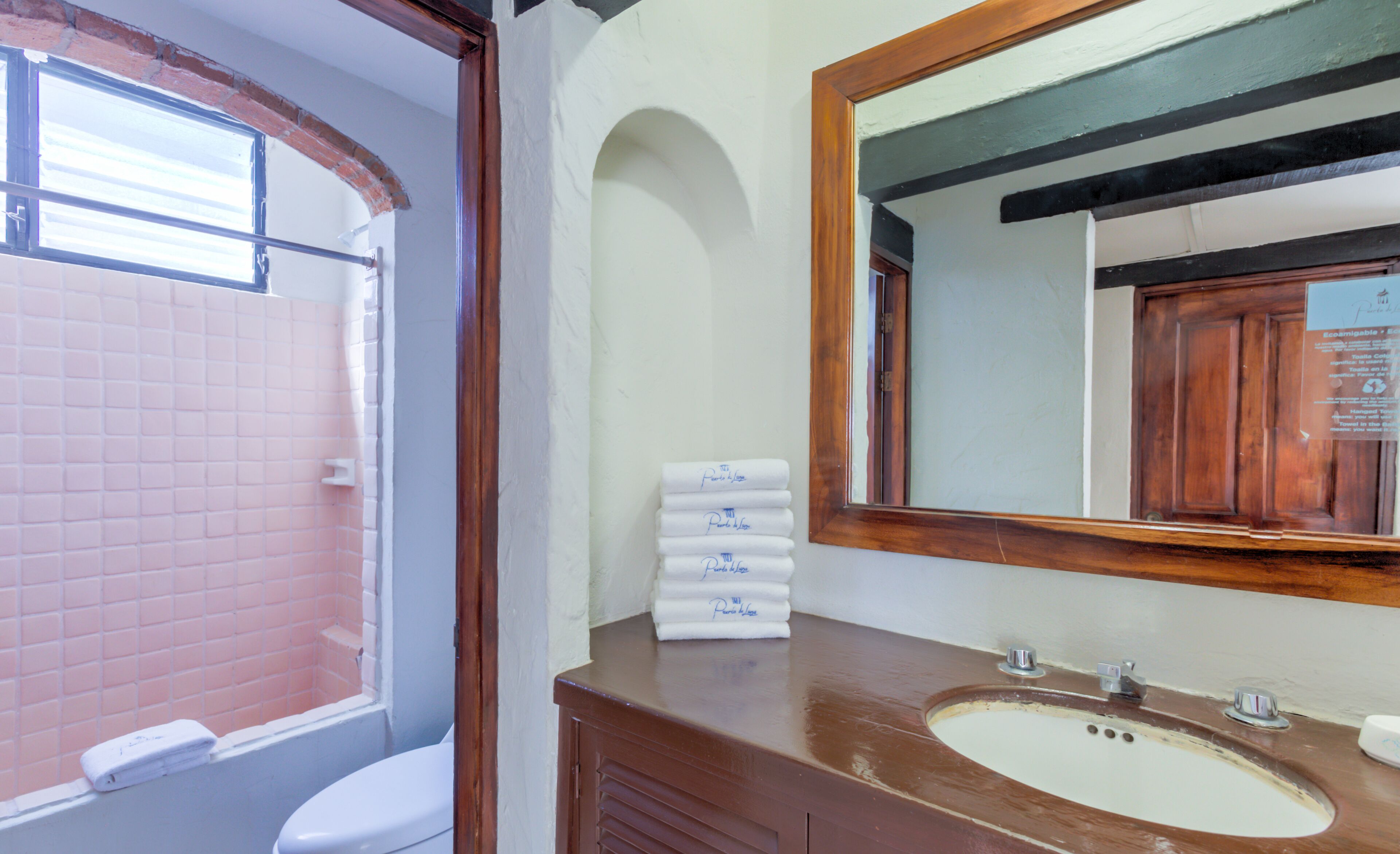 A bathroom with a white toilet, a sink with a wooden vanity, and a mirror above the sink.