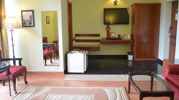 A living room with a television, a small refrigerator, a wooden cabinet, and a red sofa.