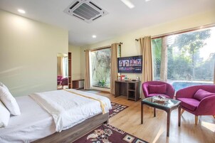 Una habitación de hotel con una cama, televisión, una mesita y un sofá.