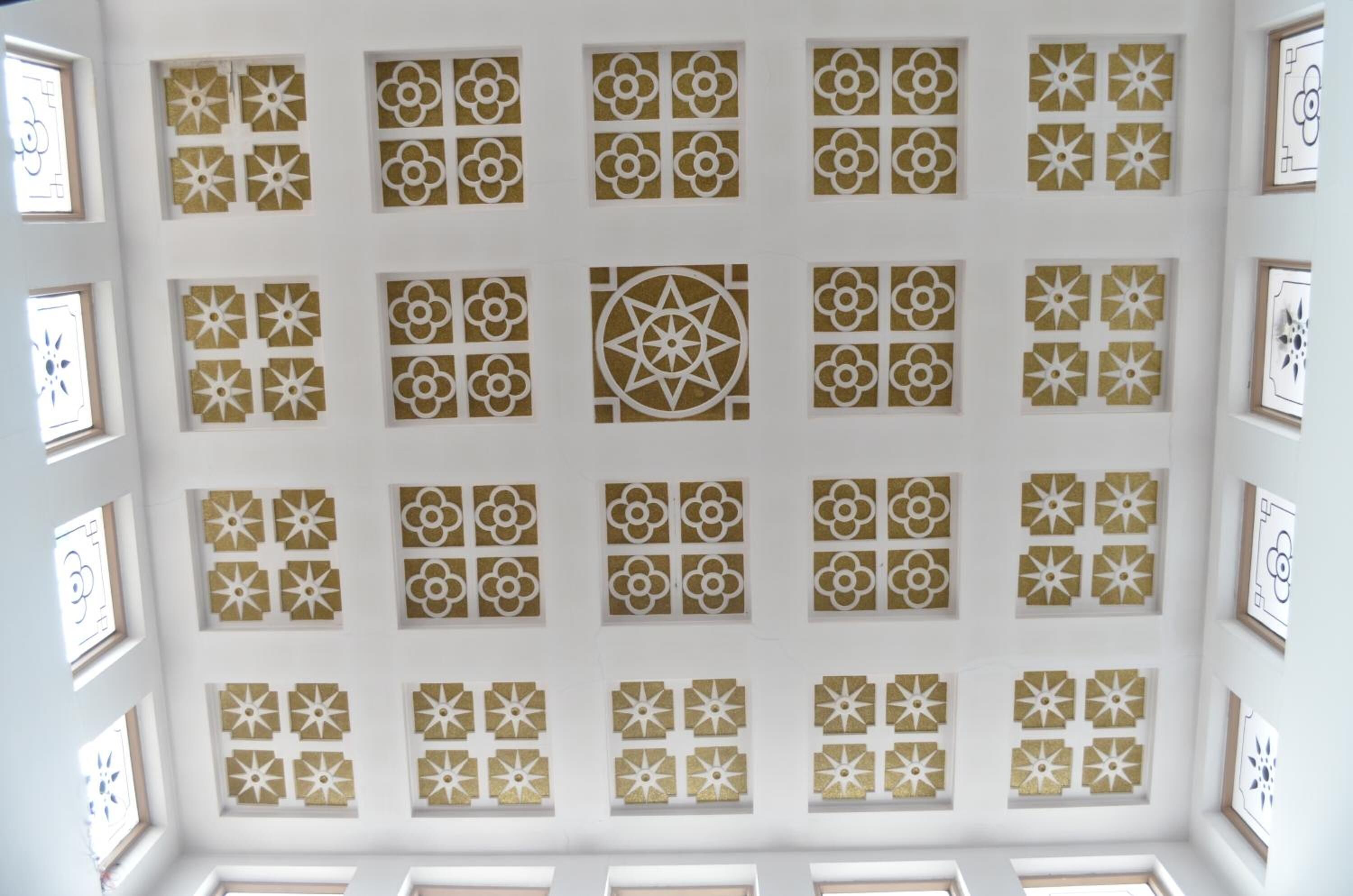 Un techo con una cuadrícula de paneles decorativos, cada uno con un patrón geométrico único.