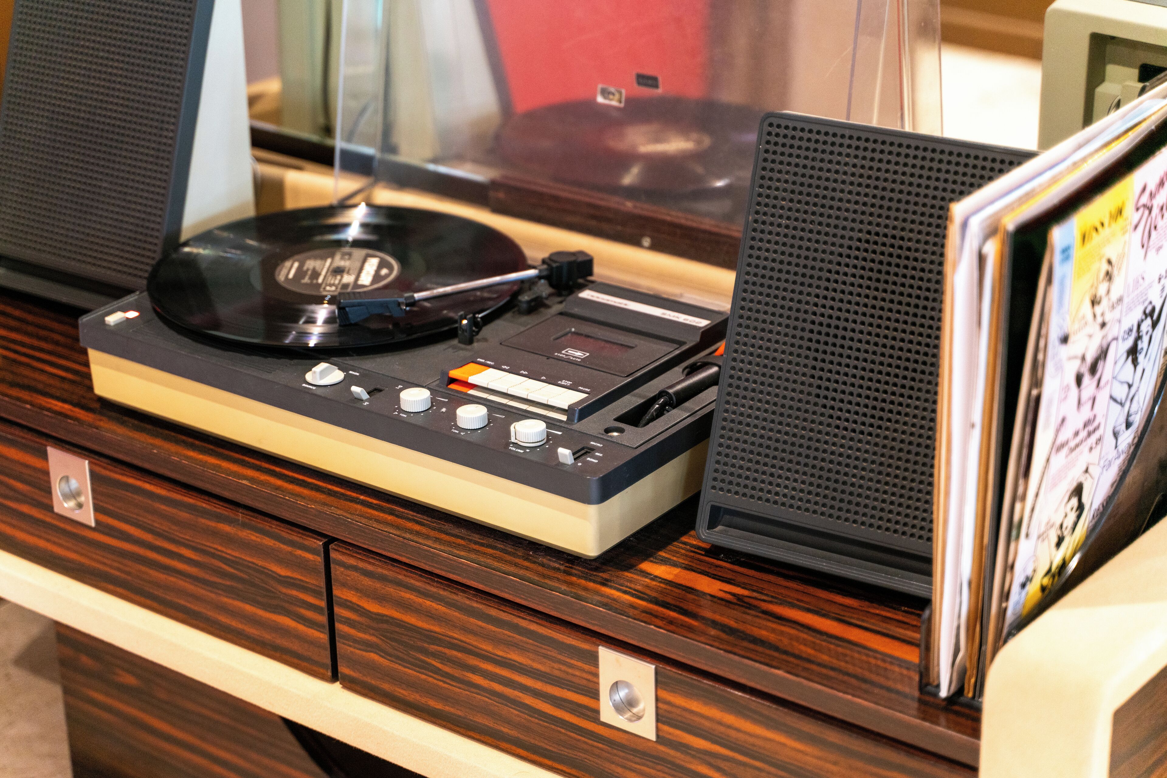 Uma mesa de madeira com um toca-discos, um alto-falante e uma revista.
