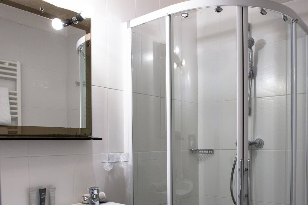 A modern bathroom with a glass-enclosed shower, a white sink, and a mirror above the sink.