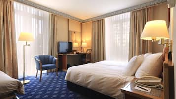 Une chambre d’hôtel équipée d’un lit, d’un bureau, d’une chaise, d’une télévision et de lampes.